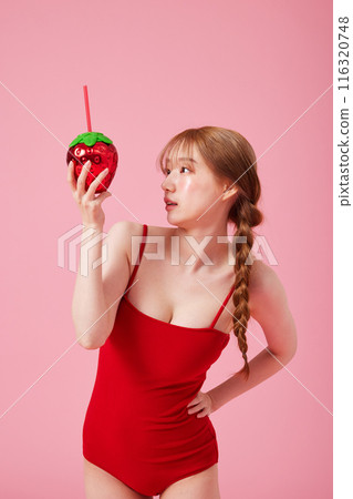 Korean woman in her 20s posing with a strawberry shaped drink in a monokini look 116320748