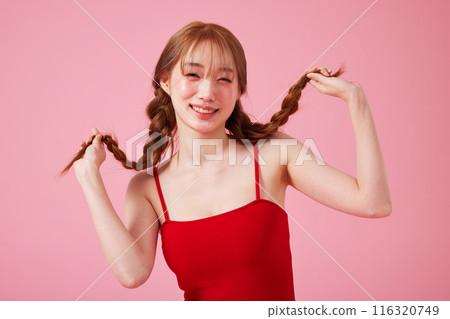A Korean woman in her 20s who wears a monokini look with a pink background and touches pigtails 116320749