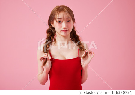 A Korean woman in her 20s who wears a monokini look with a pink background and touches pigtails A Korean woman in her 20s who wears a monokini look with a pink background and touches pigtails 116320754