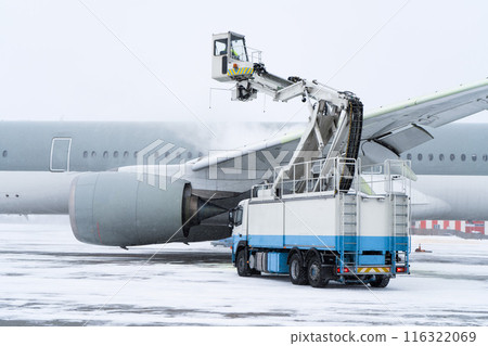 De-icing the aircraft before the flight. The deicing machine sprinkles the wing of a passenger plane with antifreeze. Winter at the airport. Snow. Aviation handling. Steam. Airport service 116322069