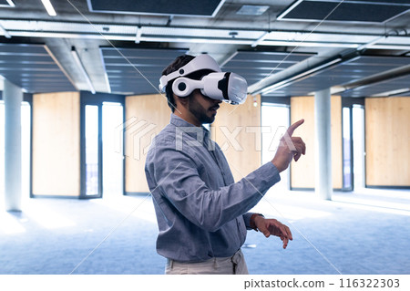 Using VR headset, man interacting with virtual interface in modern office, copy space 116322303