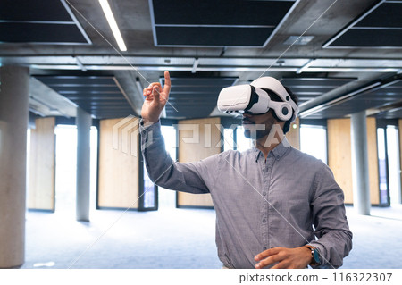 Using VR headset, man interacting with virtual interface in modern office, copy space 116322307