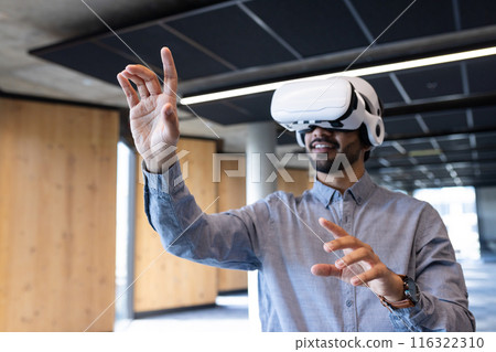 Using VR headset, man interacting with virtual environment in modern office Using VR headset, man interacting with virtual environment in modern office 116322310