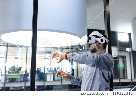 Using VR headset, man interacting with virtual environment in modern office, copy space 116322316