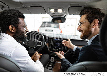 Caucasian car dealer with African American buyer inside vehicle Caucasian car dealer with African American buyer inside vehicle 116322540