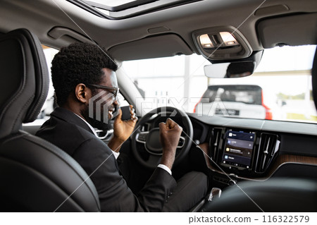 Businessman buying car and sitting inside vehicle at dealership Businessman buying car and sitting inside vehicle at dealership 116322579
