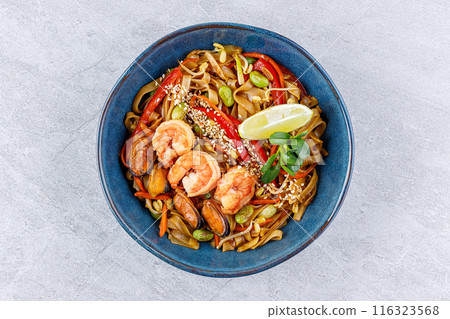 Rice noodles with shrimp and vegetables on a gray background in a blue plate for restaurant menu Rice noodles with shrimp and vegetables on a gray background in a blue plate for restaurant menu 116323568