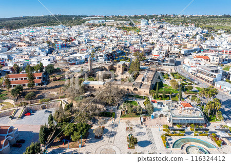Aerial view of Ayia Napa cityscape with ancient monastery and modern buildings on sunny day Aerial view of Ayia Napa cityscape with ancient monastery and modern buildings on sunny day 116324412