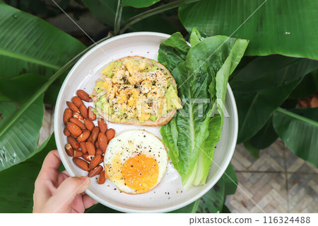 bread with egg and avocado topping with sunny side up egg , lettuce and almond bread with egg and avocado topping with sunny side up egg , lettuce and almond 116324488
