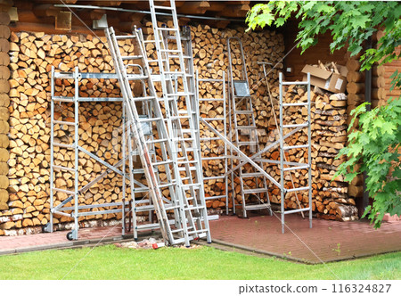 Backyard in summer. Firewood and stepladders of different heights. Organisation of working space. Outside behind house.  116324827