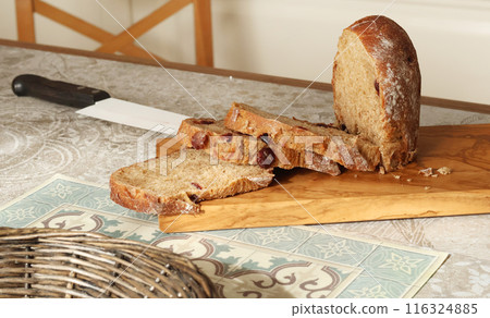 Homemade sliced rye bread with cranberries on wooden board. Kitchen interior. Food and health.  116324885