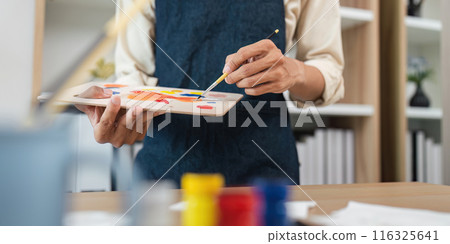 Artist Painting in Studio with Palette and Brush, Creative Process, Close Up of Hands, Art Supplies in Background 116325641