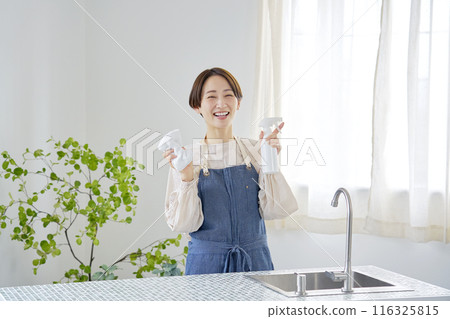 Portrait of a housewife cleaning the kitchen, looking at the camera Portrait of a housewife cleaning the kitchen, looking at the camera 116325815