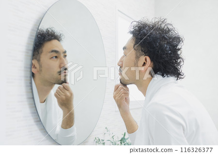 A man suffering from skin problems while looking in the mirror 116326377