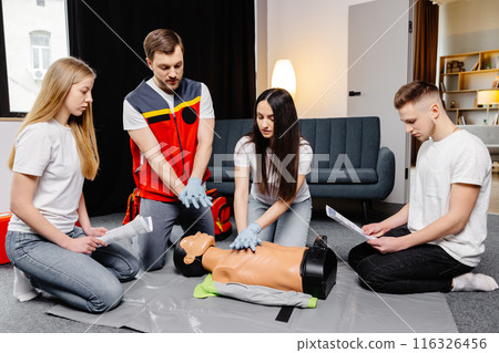 Group of people learning how to make first aid heart compressions with dummies during the training indoors Group of people learning how to make first aid heart compressions with dummies during the training indoors 116326456