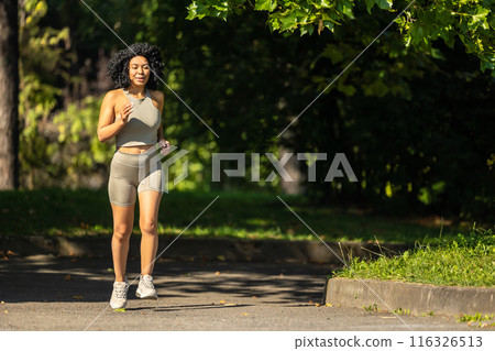 Woman in summer sportswear running in a sunny par and looking focused Woman in summer sportswear running in a sunny par and looking focused 116326513