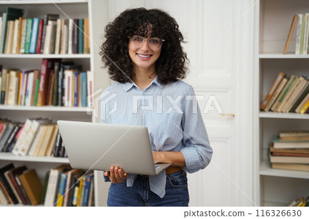 Woman student using laptop computer preparing for exams in college library 116326630