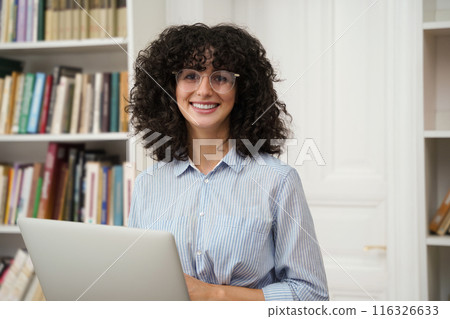 Woman student using laptop computer preparing for exams in college library 116326633
