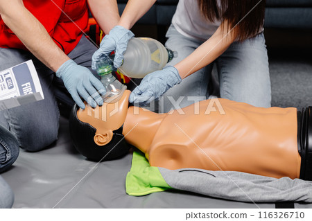 Woman holding breathing bag Ambu bag.Demonstrating CPR Cardiopulmonary resuscitation training medical procedure on CPR doll in the class.Paramedic demonstrate first aid practice for save life Woman holding breathing bag Ambu bag.Demonstrating CPR Cardiopulmonary resuscitation training medical procedure on CPR doll in the class.Paramedic demonstrate first aid practice for save life 116326710