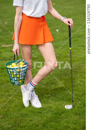 Woman golfer with golf balls on green summer field 116326790