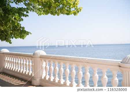 Seaside balcony with classic white balustrade and green leaves. Seaside balcony with classic white balustrade and green leaves. 116328000