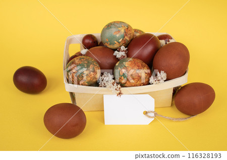 Natural Dyed Easter Eggs in Basket with Tag on Yellow Background Natural Dyed Easter Eggs in Basket with Tag on Yellow Background 116328193