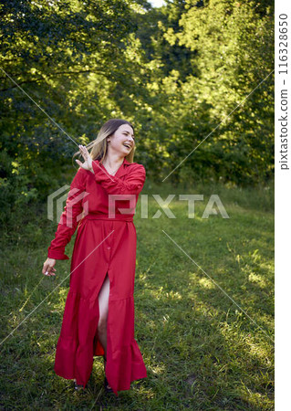 portrait of a beautiful 30-year-old woman with long blond hair in a red dress in a park portrait of a beautiful 30-year-old woman with long blond hair in a red dress in a park 116328650