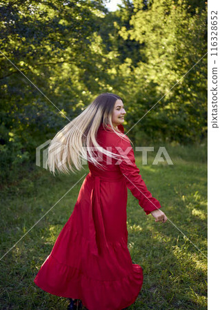 portrait of a beautiful 30-year-old woman with long blond hair in a red dress in a park portrait of a beautiful 30-year-old woman with long blond hair in a red dress in a park 116328652