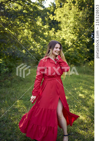 portrait of a beautiful 30-year-old woman with long blond hair in a red dress in a park portrait of a beautiful 30-year-old woman with long blond hair in a red dress in a park 116328653