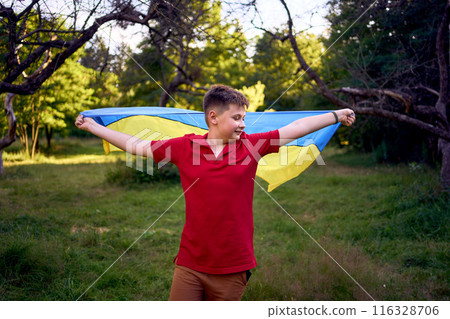 a preteen boy runs in the park with the flag of Ukraine 116328706