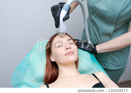A woman is getting a facial treatment with a machine 116329217