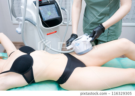 A woman is getting a leg waxed in a medical setting 116329305