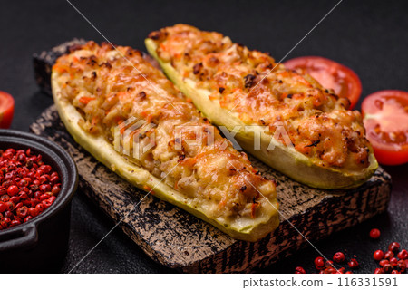 Zucchini halves baked with cheese, tomatoes, meat or meat substitute 116331591