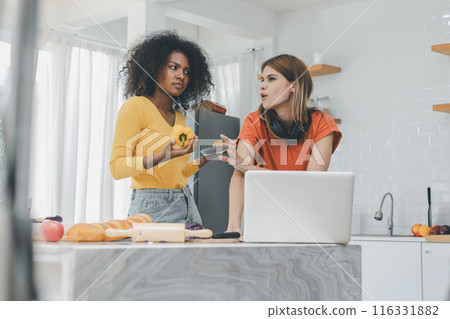 Multiethnic lesbian couple having embracing in kitchen room. Multiethnic lesbian couple having embracing in kitchen room. 116331882