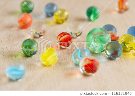 Colorful marbles arranged on a wooden board Colorful marbles arranged on a wooden board 116331943