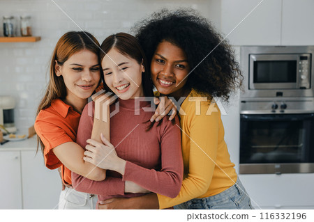 Multiethnic lesbian couple having embracing in kitchen room. Multiethnic lesbian couple having embracing in kitchen room. 116332196