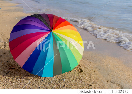 Rainbow color of umbrella on white sand beach.  116332982