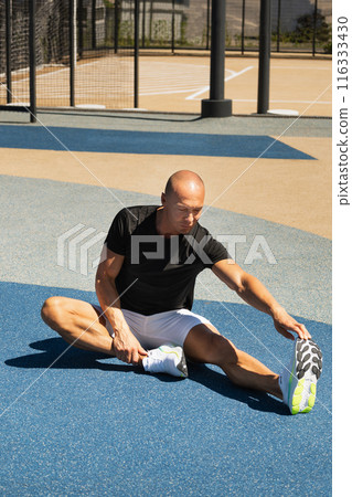 Athlete stretching legs after workout or run in public park. Outdoors training. Morning routine. Summer workout . 116333430