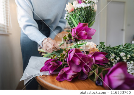 Florist Arranging Colorful Flowers on Wooden Table in Bright Room with Natural Light 116333760