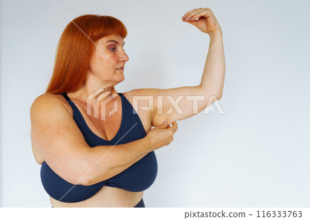 portrait red-haired middle-aged woman, plump, with large bust size, doing fitness at home 116333763