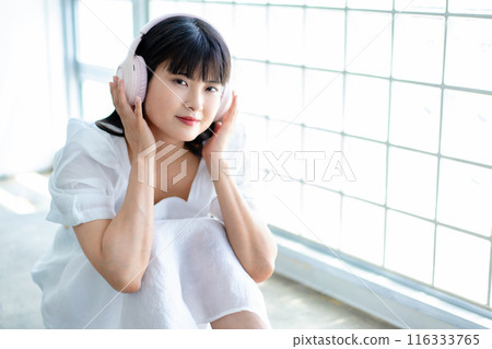 A young woman listening to music with headphones A young woman listening to music with headphones 116333765