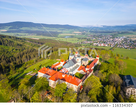 An aerial view of Hora Matky Bozi Monastery, located in Dolni Hedec near Kraliky, Czechia. The monastery is surrounded by lush greenery and a scenic landscape. An aerial view of Hora Matky Bozi Monastery, located in Dolni Hedec near Kraliky, Czechia. The monastery is surrounded by lush greenery and a scenic landscape. 116334307