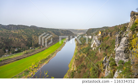Overlooking the serpentine Elbe River, a visitor enjoys the vista from Bastei Bridge in Saxon Switzerland National Park. Kurort Rathen, Germany 116334352