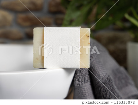 Soap bar with blank label on vessel sink near grey towels and green plant close up, mockup Soap bar with blank label on vessel sink near grey towels and green plant close up, mockup 116335078