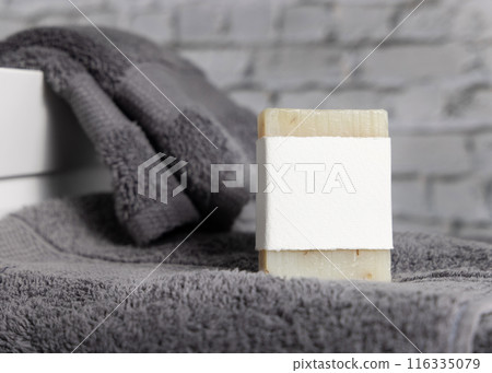 Soap bar with blank label on dark grey towels near vessel sink in bathroom closeup, mockup 116335079
