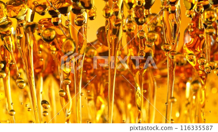 Freeze Motion Shot of Splashing Oil on Golden Background 116335587