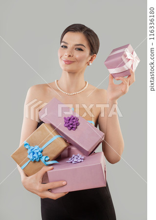 Happy excited young woman holding present gift box posing against white studio wall background . 116336180