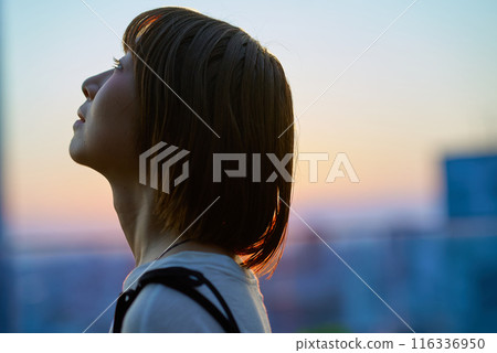 Portrait of a young woman standing in the city during magic hour Portrait of a young woman standing in the city during magic hour 116336950