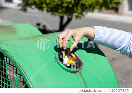 Female Hand throwing plastic bottle caps into an urban recycling bin. Recycle and reuse concept for an environmentally and globally friendly approach Female Hand throwing plastic bottle caps into an urban recycling bin. Recycle and reuse concept for an environmentally and globally friendly approach 116337255