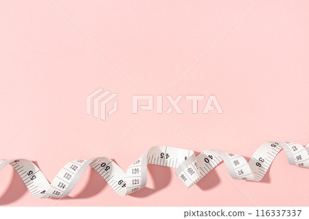 Measuring tape on pink background with copy space. Weight or length concept 116337337